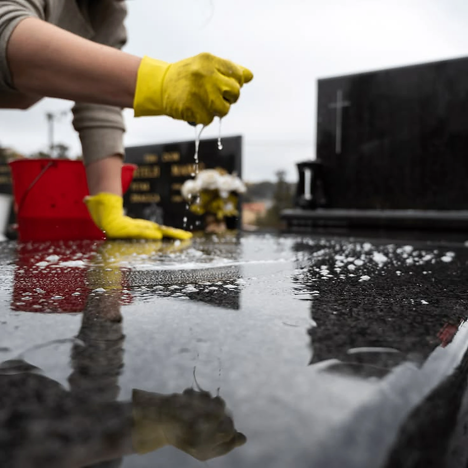 Rinsing soapy water from a polished black granite memorial